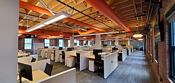 A photo of an open office floorplan. Exposed brick office. HubSpot's Cambridge HQ
