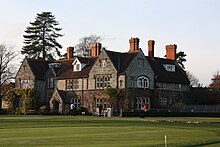 Edificio de piedra de dos pisos detrás de un campo de golf