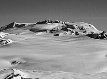 Black and white photo of a flat-topped, snow-covered mountain summit.