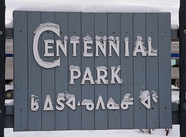 A sign in Sioux Lookout, Ontario, with Ojibwe syllabics. The partially pointed syllabics text says ᑳᐃᔑᐊᓉᐱᓈᓂᐗᐣᐠ (Gaa-izhi-anwebinaaniwang, "the place w