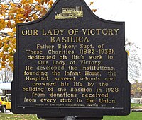 A sign describing the basilica's important status amongst Father Nelson Baker's several charitable institutions of Our Lady of Victory parish. Our Lady of Victory Institutions Sign.jpg