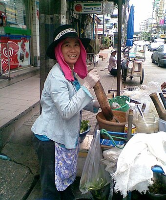 Street vendor from Isan pounding green papaya salad in Bangkok