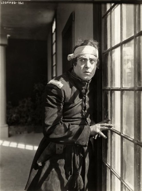 Robert Z. Leonard, costumed as a U.S. Army first lieutenant during the Civil War, pauses by a window in a scene still for the 1915 silent drama Betty'