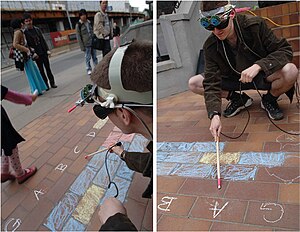 Scratching a stick on bricks and mortar, with vision-assisted gesture recognition. This gives better results than scratch input alone. (Public performance in Toronto, Ontario; image from the 2007 paper.) Scratch Input musical cyborg.jpg