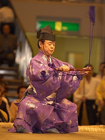 A gyōji, indicated by the solid purple tassels on his outfit.