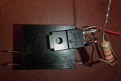 a black rectangular power transistor and relay in a black rectangular prism case are shown wired together to make a relay driving circuit