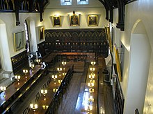 View towards the High Table in the dining hall of Merton College, Oxford. The lower tables have a mixture of chair and bench seating. The Hall, Merton College, Oxford-geograph-3159217.jpg