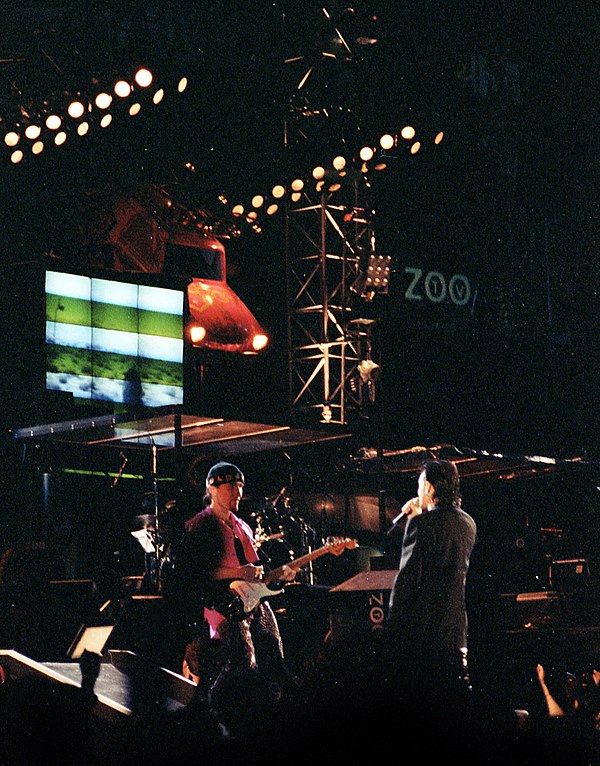 The Edge and Bono during an August 1992 show, with one of the Trabants from the lighting system visible behind them