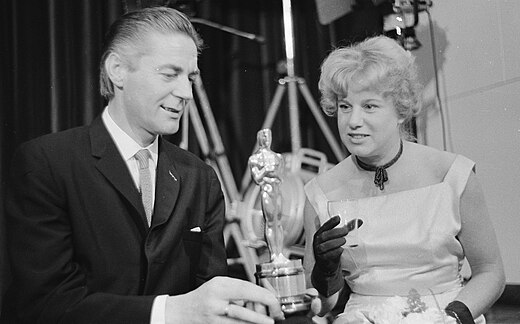 Bert Haanstra neemt een Oscar in ontvangst (1960). Rechts echtgenote Nita Wijtmans.
