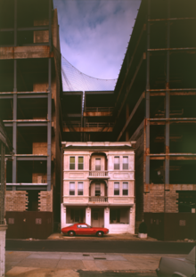 Coking house at 127 S Columbia Pl, between the steel framework of the planned Penthouse Casino; photographed by Jack Boucher for Historic American Buildings Survey, c.1991 View of house between two casinos - Town of Atlantic City, North end of Absecon Island, South of Absecon Channel, Atlantic City, Atlantic County, NJ HABS NJ,1-ATCI,19-3 (CT).tif