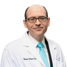 Fotografía de Michael Greger con bata blanca y corbata de colores brillantes con fondo transparente