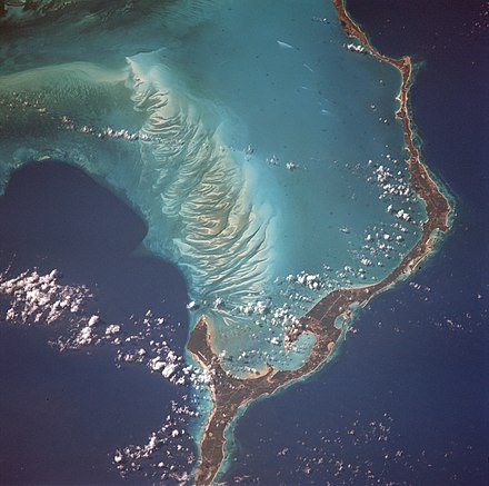 Eleuthera Island is one of several within the archipelago surrounded by shallow seas, visible here as light blue. Mosaic patterns of sand waves built by sea bottom currents in the shallows stand out in stark contrast to the deep blue of the ocean depths of a thousand feet in the Exuma Sound.