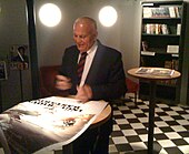 A man in a suit signing a film poster