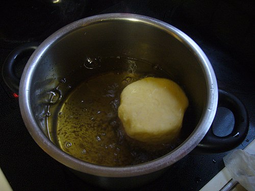 Frying a carnival doughnut in a pan.