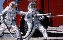 Firefighters training at a U.S. Air Force base in fire proximity suits Fire fighters practice with spraying equipment, March 1981.jpg