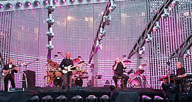 Genesis performing at Old Trafford, Manchester in 2007. From left to right, Daryl Stuermer on bass, Mike Rutherford on guitar, behind him Chester Thompson on drums, Phil Collins on vocals and Tony Banks on keyboards.