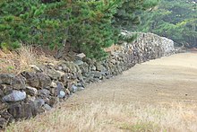 Fotografia di un basso muro a secco in pietra a vista.