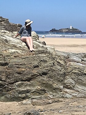 Pretty girl on rocks with lighthouse in the background