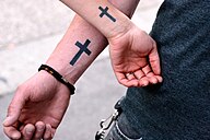 Arms with matching cross symbol tattoos