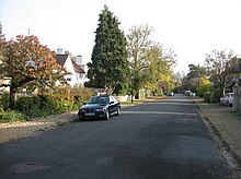 Photograph of Millington Road, looking south, with various trees and cars lining the road