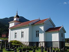 Foto einer weißen Holzkirche mit Grabsteinen im Vordergrund