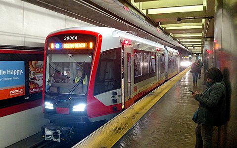 A red modern light rail vehicle at a subway platform.