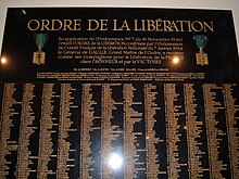 Foto de uma placa preta com linhas de nomes em letras douradas
