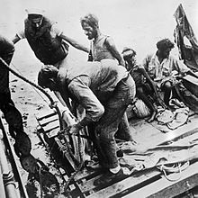 Crewmen of USS PC-576 (left) helping van der Slot (centre) out of the raft. Hoogendam and Izzi are sitting on the right. Overlevenden van de Zaandam (1943).jpg