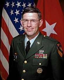 A white man in a US Army uniform is facing the camera, smiling and looking into it.