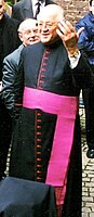 Richard Schulte-Staade, kapelaan van Zijne Heiligheid in klein paars: zwarte soutane met paarse bies, paarse sjerp, maar zonder paars solideo, pectorale en bisschopsring.