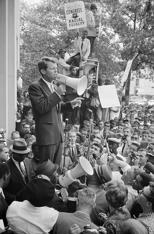 Robert F. Kennedy speaking to a crowd of African Americans and whites through a megaphone outside the Justice Department.