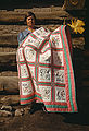 From History of quilting a 1940 Kodachrome photograph of Mrs. Bill Stagg of Pie Town, New Mexico displaying her embroidered and patchwork quilt in front of her log cabin home. Featured picture.