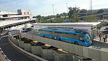 Синий сочлененный автобус на остановке аэропорта