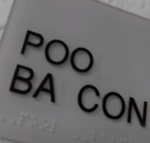 Vandalism on a sign in front of a high school pool entrance, reading: "POO BACON" Vandalized sign reading "POO BACON".png