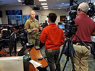 Photographie d'un général en tenue de l'armée américaine parlant devant un caméraman et un ingénieur du son.
