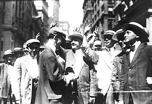 Stock trading on the New York Curb Association market on Broad Street circa 1916, with brokers and clients signalling from street to offices. Many members used flamboyant hand signals to conduct trades. Curb market.jpg