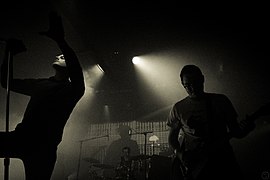 Концерт Deafheaven в августе 2013 года, левый певец Джордж Кларк, правый гитарист Керри Маккой, центральный защитник барабанщик Дэниел Трейси.