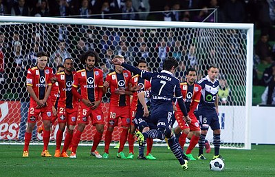 Guilherme Finkler (blue, no. 7) attempts to score from a direct free kick for Melbourne Victory FC