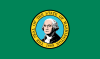 Eine grüne Flagge mit einem kreisförmigen Siegel, das aus konzentrischen Kreisen besteht.  Die inneren Kreise enthalten das Bild eines stattlichen Mannes, der eine gepuderte Perücke trägt.  Der äußere Kreis hat die Wörter 