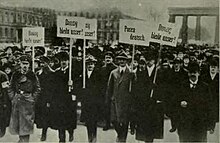 A crowd of people, holding plaques, walk towards the camera.