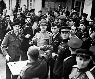 Photo noir et blanc d'une quarantaine d'hommes en uniforme, cinq au premier rang prenant un verre en main.