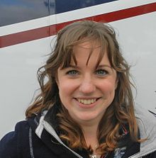 Photo of Natasha Baker smiling; she has dark brown, wavy hair and green eyes