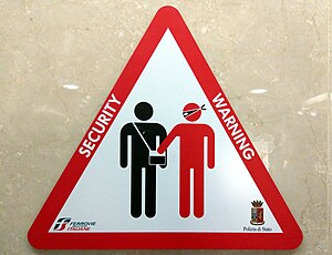 Red, black and white placard warning sign displayed in a public facility, with surrounding text "SECURITY WARNING"