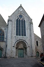 façade de l'église Saint-Nicolas de Saint-Arnoult-en-Yvelines montrant un portail de style roman surmonté d'une haute verrière