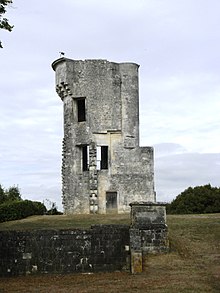 The ruins of a stone structure in an open field of grass.