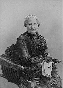 Head and shoulders sepia photograph showing an older woman with gray hair and wearing a dark lace dress