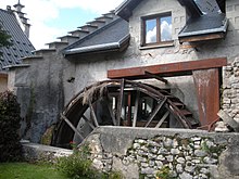 Foto der Fassade einer alten Wassermühle mit ihrem Rad.