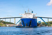 Cosco Shipping Zhi Yan Kou in Curacao carrying three smaller vessels on board. Zhi Yuan Kou on front of Queen Juliana Bridge in Curacao.jpg