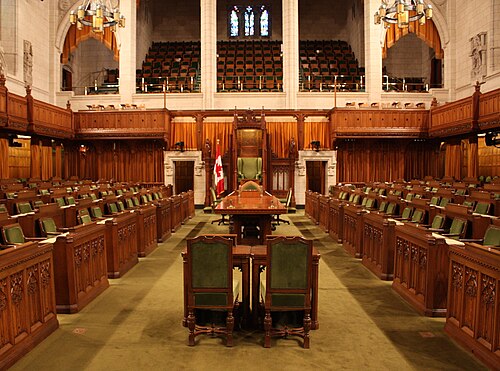 The chamber of the House of Commons; the Speaker's chair is front and centre in the room.
