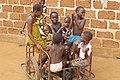 Enfants jouant Sékou (Bénin) en se transportant à l'aide d'une charrette à deux roues appelé Pousse-pousse au Bénin.jpg